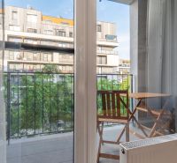 Výhled z 1-pokojového bytu na balkon se stolem a židlemi.