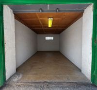 Otevřená garáž s dřevěným stropem a betonovou podlahou.