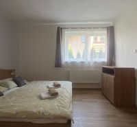 Jednoduše zařízená ložnice s postelí a podlahou s dřevěným dekorem v dvoupokojovém bytě.