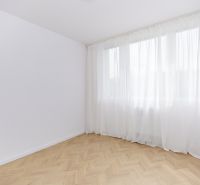Prostorný pokoj s podlahou s dřevěným dekorem a bílými závěsy ve 4pokojovém bytě.