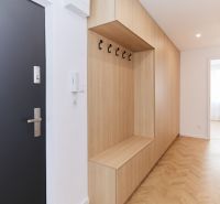 Chodba s vestavěným nábytkem a podlahou s dřevěným dekorem ve 4pokojovém bytě.