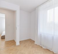 Pokoj s bílými závěsy a podlahou s dřevěným dekorem ve 4-pokojovém bytě.