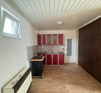 Kuchyňská linka s červenými skříňkami a podlahou s dřevěným dekorem v 2-pokojovém bytě.