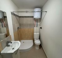 Koupelna v 2-pokojovém bytě s vanou, umyvadlem a toaletou, světlé obklady stěn.