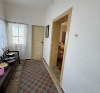 Chodba v rodinném domě s dlaždicovou podlahou, bílými stěnami a jednoduchým zařízením.