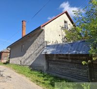Rodinný dům v Šumiaci s plechovou střechou, sousedící se zelenou přírodou a silnicí.
