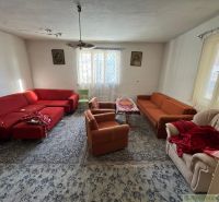 Obývací pokoj v rodinném domě s červenými a oranžovými sedačkami a kobercem.