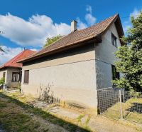 Rodinný dům v Pažiti obklopený zelení, s červenou střechou a dřevěnými okny.