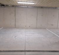 Podzemní garáž s betonovou podlahou a osvětlením.