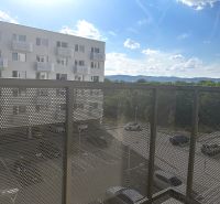 Balkon v 1-pokojovém bytě s výhledem na parkoviště a okolní hory.