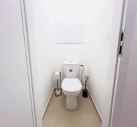 Toaleta s bílými stěnami v 2-pokojovém bytě, jednoduché sanitární vybavení.