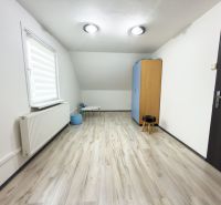 Pokoj v rodinném domě s podlahou s dřevěným dekorem a jednoduchým nábytkem.