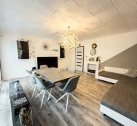 Obývací pokoj v rodinném domě s podlahou s dřevěným dekorem a elegantním osvětlením.
