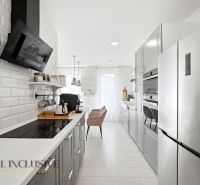 Stylová kuchyně v rodinném domě s moderními spotřebiči a bílým obložením.