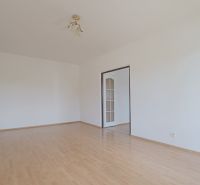 Pokoj s podlahou s dřevěným dekorem v 3-pokojovém bytě, jednoduché bílé stěny.