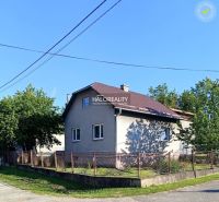 Rodinný dům v Margecanech se šikmou střechou, oplocený, obklopený zelení a modrou oblohou.
