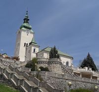 Kostel s věží obklopený schodištěm a zelení v Ružomberku.