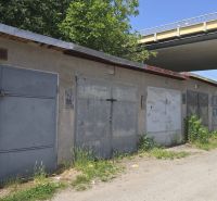 Garáže na Jesenského ulici ve Zvolenu podél cesty se zelení a graffiti.