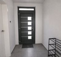 V interiéru vidíme vchodové dveře, bílé stěny a dlažbu s klíči na podlaze.