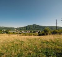 Krajina s travnatým pozemkem a elektrickými sloupy na Partizánské cestě, Banská Bystrica. Pozemky - bydlení.