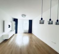 Obývací pokoj v 3-pokojovém bytě s podlahou s dřevěným dekorem a závěsnými lampami.