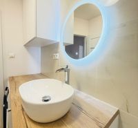 Koupelna v 3-pokojovém bytě s designovým umyvadlem a osvětleným zrcadlem.