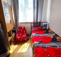 Pokoj ve 4pokojovém bytě s postelí, skříní a podlahou s dřevěným dekorem.