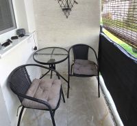 Balkon ve 4pokojovém bytě se dvěma židlemi a stolkem na dlažbě.