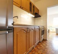 Kuchyně s dřevěnými skříňkami v 2-pokojovém bytě, podlaha s dřevěným dekorem.