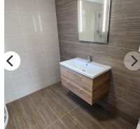Koupelna v 1-pokojovém bytě s podlahou a stěnami v dřevěném dekoru.