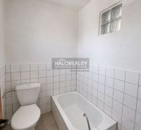 Koupelna v rodinném domě s vanou, toaletou a bílými obklady.