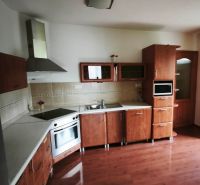 Kuchyně s dřevěným dekorem, vestavěné spotřebiče a rohové skříňky v rodinném domě.
