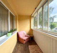 Balkon 4pokojového bytu s posezením a podlahou s dřevěným dekorem.