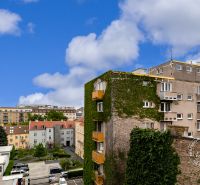 Pohled na budovy a ulice Bratislavy se zelení a modrou oblohou.