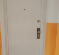 Bílé dveře na chodbě 4-pokojového bytu s oranžovými stěnami.