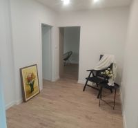 Interiér 4-pokojového bytu s podlahou s dřevěným dekorem, křeslem a obrazem.