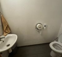 Toaleta s umyvadlem a dlažbou. Obchodní prostory s jednoduchým vybavením.