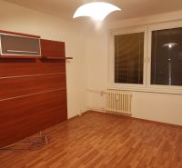 Pokoj s podlahou s dřevěným dekorem, bílými stěnami a nástěnnou skříní ve 3-pokojovém bytě.