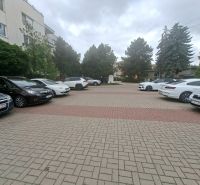 Parkoviště s auty na Športové ulici v Dunajské Lužné před budovou.