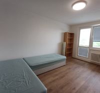 Pokoj s dvěma postelemi, regálem a podlahou s dřevěným dekorem ve 3-pokojovém bytě.