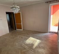 Obývací pokoj v 3-pokojovém bytě s podlahou s dřevěným dekorem a lustrem.