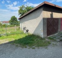 Garáž se zavřenými dveřmi na Haburské ulici v Prešově vedle travnatého pozemku.