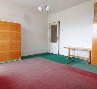 Prázdný pokoj v rodinném domě s nábytkem a zeleným kobercem.