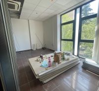 Kanceláře s velkými okny, klimatizací a nepořádkem, podlaha s dřevěným dekorem.