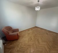 Pokoj v 2-pokojovém bytě s podlahou s dřevěným dekorem a křeslem.