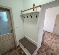 Předsíň v 2-pokojovém bytě s věšáky a podlahou s dřevěným dekorem.
