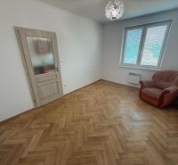 Pokoj v 2-pokojovém bytě s podlahou s dřevěným dekorem a křeslem.