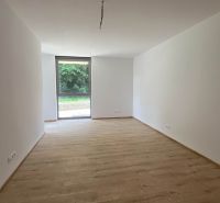 Prostorná místnost v rekreačním apartmánu s bílými stěnami a podlahou s dřevěným dekorem.