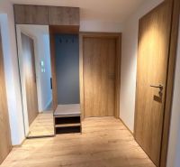 Interiér rekreačního apartmánu s podlahou s dřevěným dekorem a vestavěnou skříní s velkým zrcadlem.