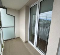 Balkon 2-pokojového bytu s dlaždicovou podlahou, zábradlím a prosklenými dveřmi.